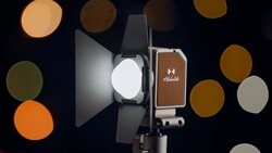Professional LED light with reflector and brown leather case displayed against blurred bokeh background.