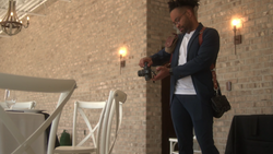 Photographer adjusting camera settings while standing in a brick-walled venue with warm accent lighting.
