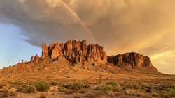 Desert butte with jagged rock formations under golden hour light and dramatic storm clouds.
