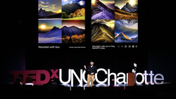 TEDxUNC Charlotte stage setup with mountain landscape photographs displayed above.