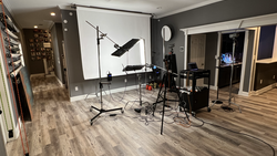 Professional photography studio setup with softbox lighting, backdrop stand, and equipment on wooden flooring.