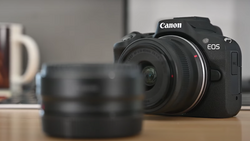 Canon EOS mirrorless camera with interchangeable lens on wooden surface.