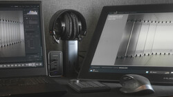 Professional audio editing workstation with dual monitors, headphones, and mixing equipment.