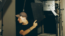 Photographer adjusting a professional LED light panel mounted on a stand in a studio setting.