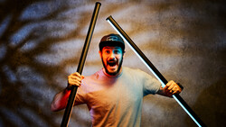 Enthusiastic man holding two poles with dramatic studio lighting and textured background.