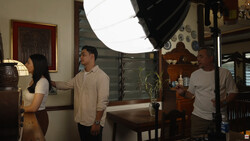 Three people setting up a portrait photography session with a large softbox and lighting equipment in an interior space.