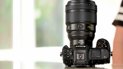 Nikon Z mirrorless camera with attached telephoto lens mounted on white surface.