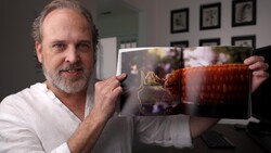 Photographer displaying an open photo book with vibrant red architectural imagery.