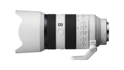 Side view of a mirrorless telephoto lens with white barrel, black focus ring, and control buttons.