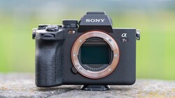 Sony a7 III mirrorless camera with lens removed, showing copper-colored mount against blurred green background.