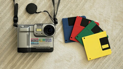 Vintage digital camera with memory cards and lens cap on neutral fabric surface.