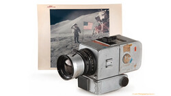 Vintage film camera with telephoto lens displayed alongside a lunar surface photograph featuring an astronaut and American flag.