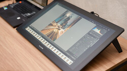 Editing display tablet showing photo of architectural golden hour scene with editing panels open.