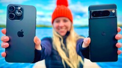 Person holding iPhone 12 Pro and Pixel 6 Pro side by side outdoors with scenic water backdrop.