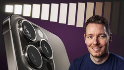Man posing next to large smartphone displaying triple-lens camera system against purple backdrop with lighting panel.