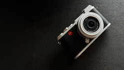 Rangefinder camera with silver top plate and black leather body on dark textured surface.