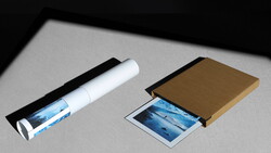 Product packaging mockups for photographic prints displayed on gray surface with dramatic side lighting.