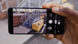 Smartphone camera app interface showing a construction site with metal railing and wooden boxes in the frame.