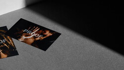 Two printed proofs with golden bokeh and warm lighting on a gray surface with dramatic shadow.