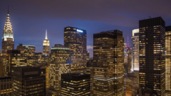 Manhattan skyline at twilight with illuminated skyscrapers including the Chrysler Building and Empire State Building.