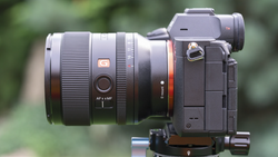 Sony mirrorless camera with wide-angle lens mounted on tripod head against blurred green background.
