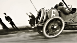 Vintage racing car number 6 captured in motion during early motorsport competition.