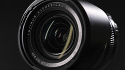 Close-up of a wide-angle lens barrel showing spherical lens elements and optical glass layers against dark background.