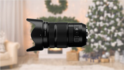 Black telephoto lens with lens hood against blurred holiday interior background.