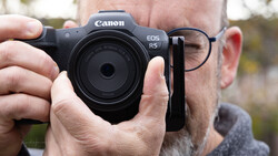 Man holding a Canon EOS R5 mirrorless camera with an RF 35mm lens attached.