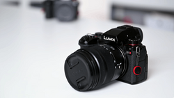 Panasonic Lumix mirrorless camera with attached prime lens on white surface.