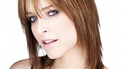 Woman with shoulder-length brown hair and bangs, looking to the side with neutral expression.