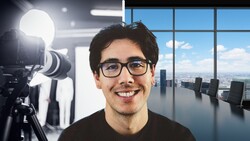 Man wearing glasses smiling at camera in modern office with professional lighting setup visible.