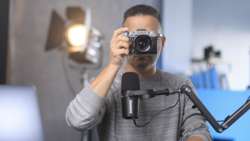 Photographer holding a vintage rangefinder camera in a studio with professional lighting setup.