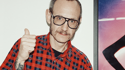 Man with glasses and mustache wearing red plaid shirt giving thumbs up gesture.
