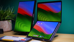 Three foldable tablet devices displaying colorful gradient wallpapers on a wooden desk with a potted plant and keyboard nearby.
