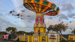 Colorful carousel ride with spinning swings in motion at an outdoor carnival or fair.