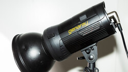 Generau studio flash with reflector mounted on stand against white background.