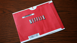 Red Netflix DVD envelope with white logo and barcode labels on wooden surface.