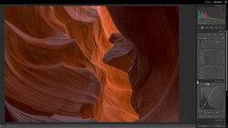 Slot canyon with smooth, flowing sandstone walls in warm orange and deep red tones under natural light.