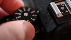 Close-up of a camera's ISO dial being adjusted by a photographer's finger.