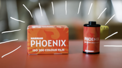 Harman Phoenix ISO 200 color film box and canister displayed on a surface with dramatic lighting.
