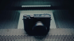 Vintage rangefinder camera with chrome accents on textured metal surface with diffused overhead lighting.