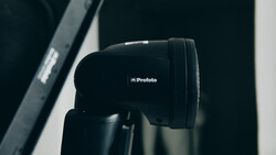 Profoto studio flash head mounted on a light stand against a dark background.