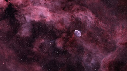 Planetary nebula surrounded by expansive magenta and pink hydrogen gas clouds against a starfield.