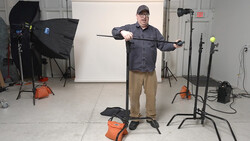 Photographer demonstrating lighting technique with reflector in professional studio setup.
