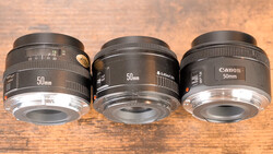 Three 50mm prime lenses arranged side by side on a wooden surface for comparison.