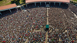 Aerial view of a massive crowd filling a stadium field during an organized event or gathering.