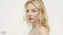 Blonde woman with wavy hair in neutral studio portrait against white background.
