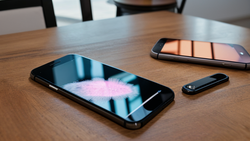 Three smartphones arranged on a wooden table displaying colorful gradient and blur effects on their screens.