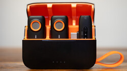 Portable wireless microphone system with charging case displaying two black microphones with orange accents and a receiver unit.